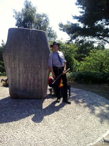 pipper vor dem Gedenkstein des ersten Pfadfinderlagers auf Brownsea Island